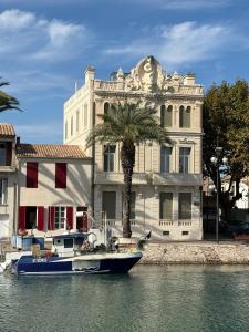 a boat in the water in front of a building at T2 Familial - 250 m front de mer, plage, seaquarium - parking privé - Bienvenue en occitanie in Le Grau-du-Roi