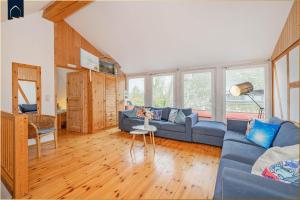 a living room with a blue couch and some windows at Ferienanlage am Gothensee 25 Rad Kapitän in Bansin
