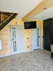 a room with two doors and a flat screen tv at Barn&Haus-Stodoły Widokowe in Zubrzyca Dolna