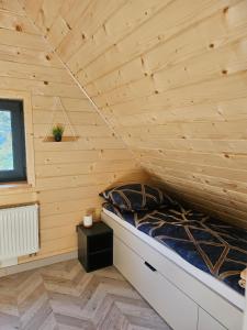 a bed in a room with a wooden wall at Barn&Haus-Stodoły Widokowe in Zubrzyca Dolna