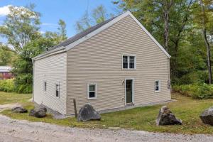 a white barn with rocks in front of it at Comfy Large Bungalow - 4 Bed 1BA On Private Pond in Bradford