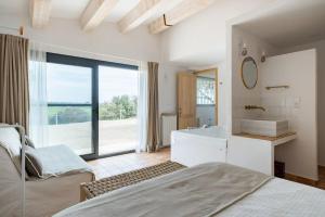 a bedroom with a bed and a tub and a sink at Mas de l'Aranyó - Eco Wellness Spa in Hostafranco