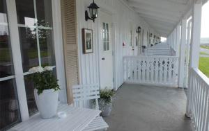 a porch of a white house with a bench and flowers at Söderby Lodge in Uppsala