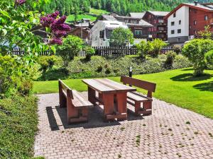 a picnic table and two benches in a park at Apartment Metropol B by Interhome in Grächen
