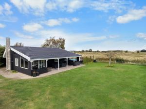 a black house with a green yard at Holiday Home Rolfkarl - 250m from the sea by Interhome in Dalby