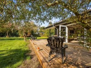 a wooden deck with a chair on a yard at Holiday Home Tameran - 1km from the sea by Interhome in Gedesby