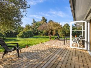 a wooden deck with a table and chairs on it at Holiday Home Tameran - 1km from the sea by Interhome in Gedesby +16 photos