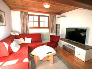 Una sala de estar con un sofá rojo y un televisor de pantalla plana. en Apartment Plank-1 by Interhome, en Stumm