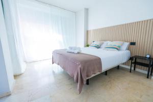 Una cama grande en una habitación con una ventana grande. en Apartamentos Maresía by Infinity Summer, en Las Palmas de Gran Canaria