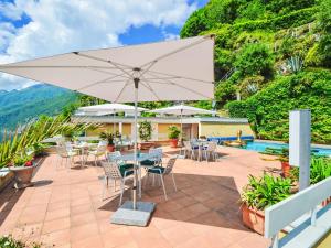 Un patio con mesas y sillas y una sombrilla. en Apartment Lakeview App- 603 by Interhome, en Moscia