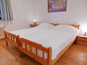 Un dormitorio con una cama de madera con un colchón blanco. en Apartment Les Arsets 01-203 by Interhome, en Taveyannaz