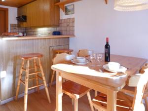 Una cocina con una mesa de madera con una botella de vino. en Apartment Les Arsets 01-203 by Interhome, en Taveyannaz