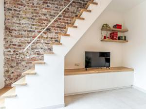 a living room with a staircase with a tv and a brick wall at Holiday Home Lili's with terrace by Interhome in Blankenberge