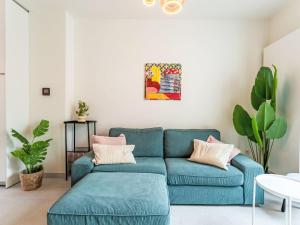 a blue couch in a white living room with plants at Holiday Home Lili's with terrace by Interhome in Blankenberge +18 photos