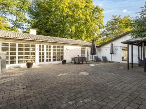a patio with a table and umbrellas in front of a building at Holiday Home Ranka - 300m from the sea by Interhome in Strøby Ladeplads
