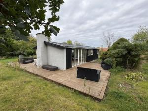 a house with a wooden deck in a field at Holiday Home Gun - 300m to the fjord by Interhome in Glostrup
