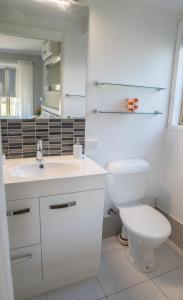 Un baño blanco con inodoro y lavabo. en Stays with Ripley 3 min to hospital and beach Pet friendly, en Urraween