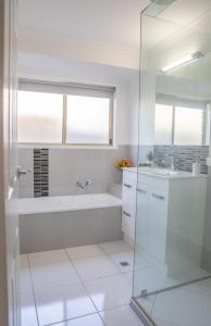 Un baño blanco con bañera y lavabo. en Stays with Ripley 3 min to hospital and beach Pet friendly, en Urraween 17 fotos más