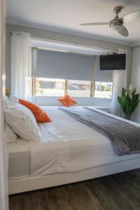 Una cama blanca grande en un dormitorio con ventana. en Stays with Ripley 3 min to hospital and beach Pet friendly, en Urraween