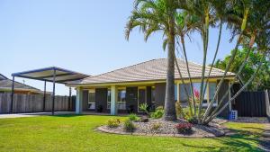 una casa con palmeras en un patio en Stays with Ripley 3 min to hospital and beach Pet friendly, en Urraween