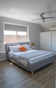 1 dormitorio con 1 cama grande con almohada naranja en Stays with Ripley 3 min to hospital and beach Pet friendly, en Urraween