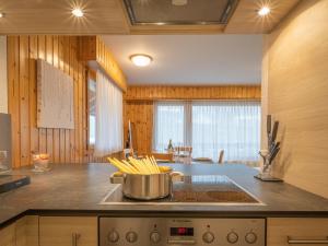 a kitchen with a stove with a pot of pasta at Apartment Eaux-Vives 201 by Interhome in Ovronnaz +23 photos