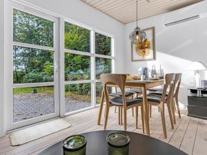 a dining room with a table and chairs and windows at Holiday Home Cornel - 300m from the sea by Interhome in Strøby Ladeplads