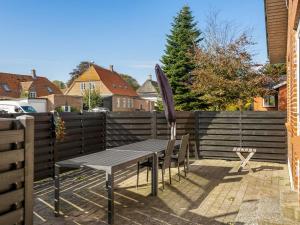 a wooden fence with a table and an umbrella at Holiday Home Wraghi - 21km from the sea by Interhome in Højer