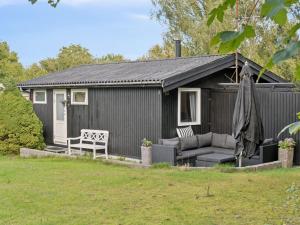 a black shed with a couch and a bench at Holiday Home Baarde - 1-2km from the sea by Interhome in Vejby