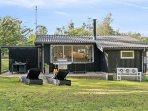 a black house with two chairs in a yard at Holiday Home Baarde - 1-2km from the sea by Interhome in Vejby