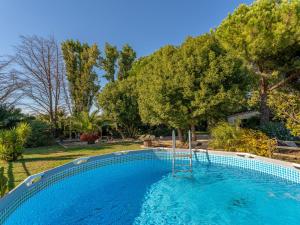 a large swimming pool in a yard with trees at Villa Palmeraie by Interhome in Hyères