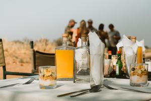 una mesa con botellas y vasos de zumo de naranja en Khanya Conservation Camp, en Phalaborwa