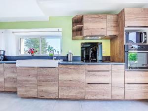 a large kitchen with wooden cabinets and a window at Holiday Home De cap en cap by Interhome in Trouguennour