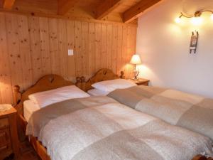 2 camas en un dormitorio con paneles de madera en Chalet Ecureuil noir by Interhome, en Ovronnaz