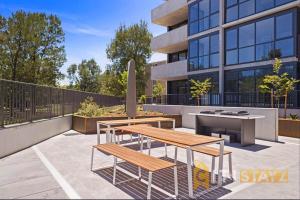 un patio avec deux bancs et une table et un bâtiment dans l'établissement Lavish in Lyneham - 2BD 1Bth Apt, à Canberra