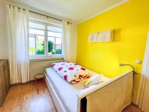 a small yellow room with a bed with a window at Apartment Bärbel by Interhome in Suhl