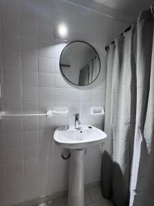 a white bathroom with a sink and a mirror at Torrejon 301 in Villa Gesell