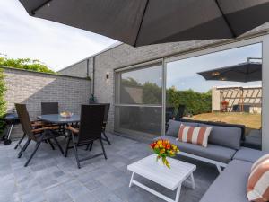 eine Terrasse mit einem blauen Sofa und einem Tisch mit Stühlen in der Unterkunft Holiday Home Casa Pepino in quiet cul de sac by Interhome in Mispelburg