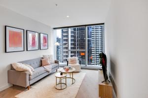 a living room with a couch and a large window at CBD Elegant 2BR Apt with Pool, Gym & City Views in Melbourne