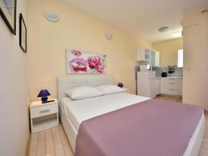 a bedroom with a white bed and a kitchen at Apartment Melandura-6 by Interhome in Dinjiška