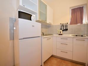 a white kitchen with a white refrigerator in a room at Apartment Melandura-6 by Interhome in Dinjiška