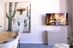 a living room with a fireplace and a painting of a woman at Tranquil & Modern Studio with Amazing Mountain View in Cape Town