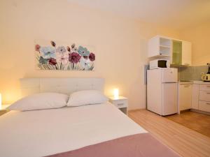 - une chambre avec un lit blanc et un réfrigérateur blanc dans l'établissement Apartment Melandura-2 by Interhome, à Dinjiška