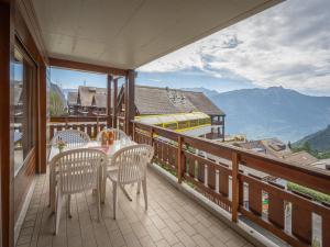 a balcony with a table and chairs and a train at Apartment Sources 4110 by Interhome in Ovronnaz