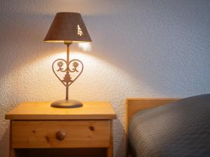 a lamp on a night stand next to a bed at Apartment Sources 4110 by Interhome in Ovronnaz