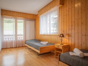 two beds in a room with wooden walls and windows at Apartment Sources 4110 by Interhome in Ovronnaz +19 photos