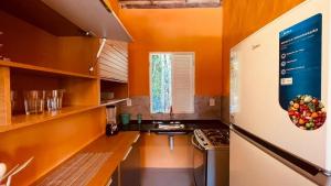 a kitchen with an orange wall and a refrigerator at Chale Encanto do Rio in Porto Seguro