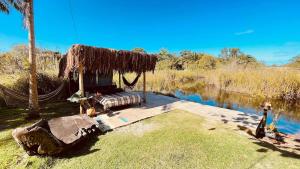 a hut with a hammock next to a body of water at Chale Encanto do Rio in Porto Seguro +4 photos