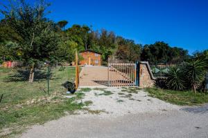 a gate in a field with a house in the background at Casale in legno nella natura laziale in La Giustiniana