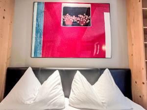 a framed picture above a couch with white pillows at Apartment Cheeky Apartment-1 by Interhome in Oberndorf in Tirol +10 photos